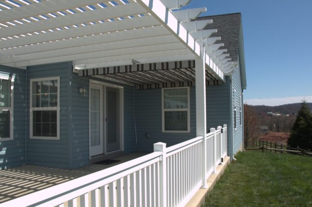 White vinyl railing kit installed around a porch, attached to a blue house, enhancing safety and aesthetics